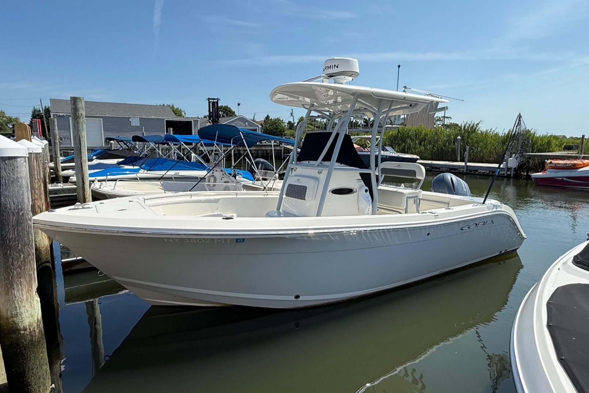Cobia 220 Center Console 2023 Cobia 220 Center Console boat docked in a marina under clear skies.