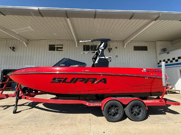 Supra SL 2021 Supra SL boat in vibrant red on a matching trailer, parked outdoors.
