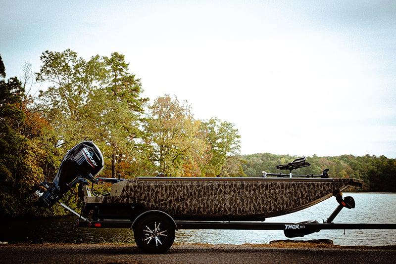 Thor FH1754 2026 Thor FH1754 boat on trailer by a lake, surrounded by trees.