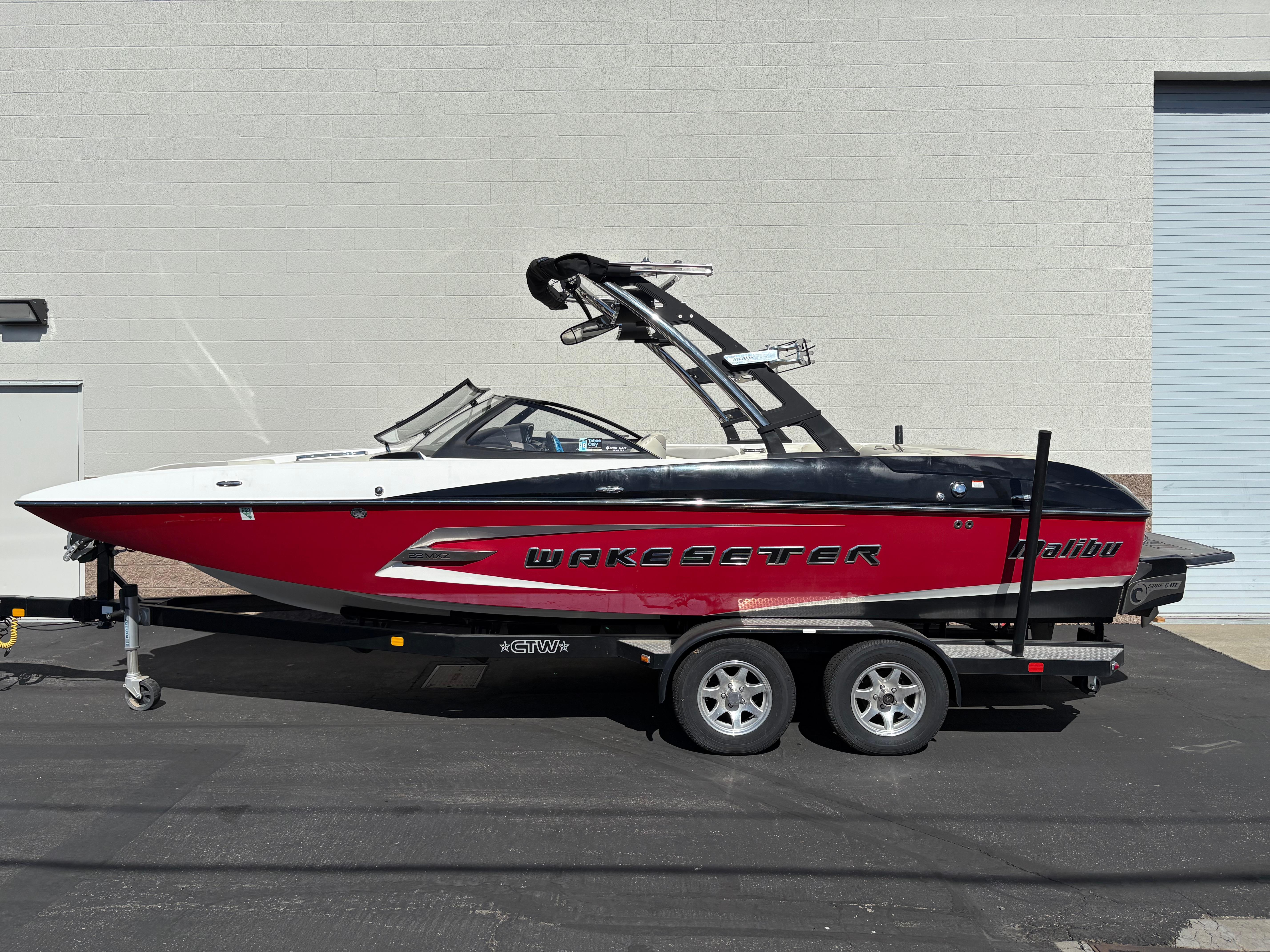 Malibu Wakesetter 22 MXZ 2014 Malibu Wakesetter 22 MXZ boat on trailer, red and white design, parked outdoors.