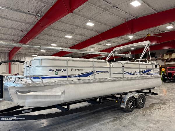 PlayCraft 2600 Powertoon 2004 PlayCraft 2600 Powertoon pontoon boat on trailer in indoor storage facility.