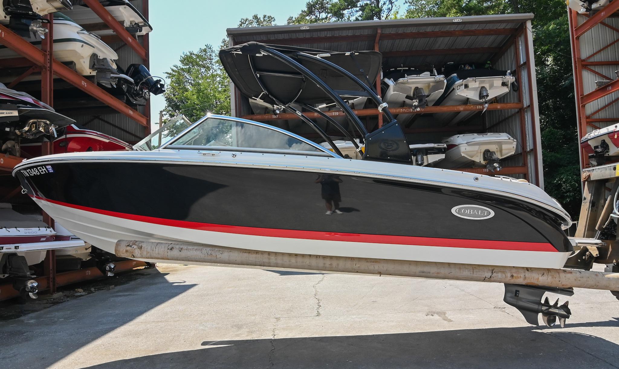 Cobalt 220 2015 Cobalt 220 boat in storage, black with red stripe, outdoor setting.
