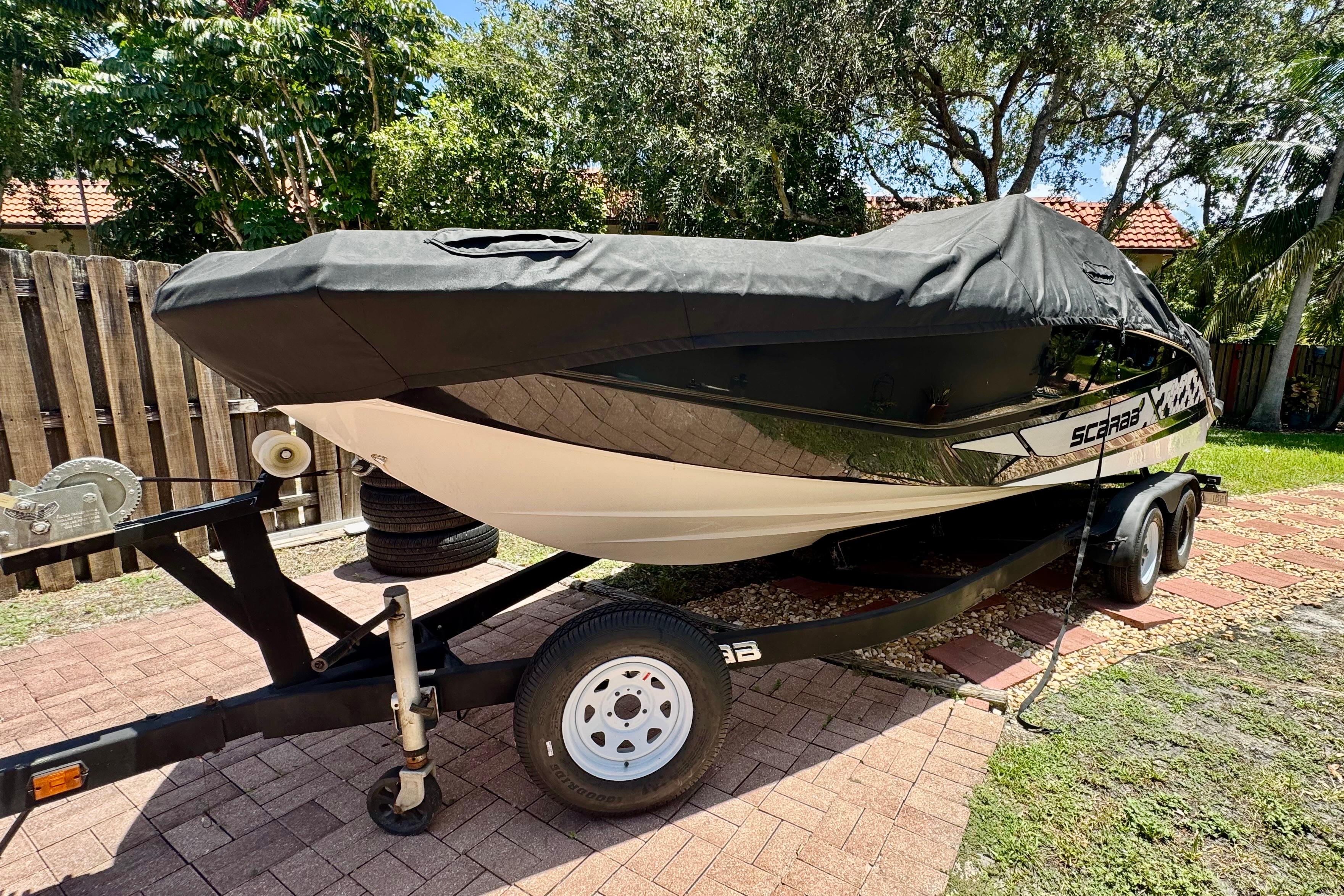 Scarab 255 G 2019 Scarab 255 G boat on trailer, covered, parked outdoors.
