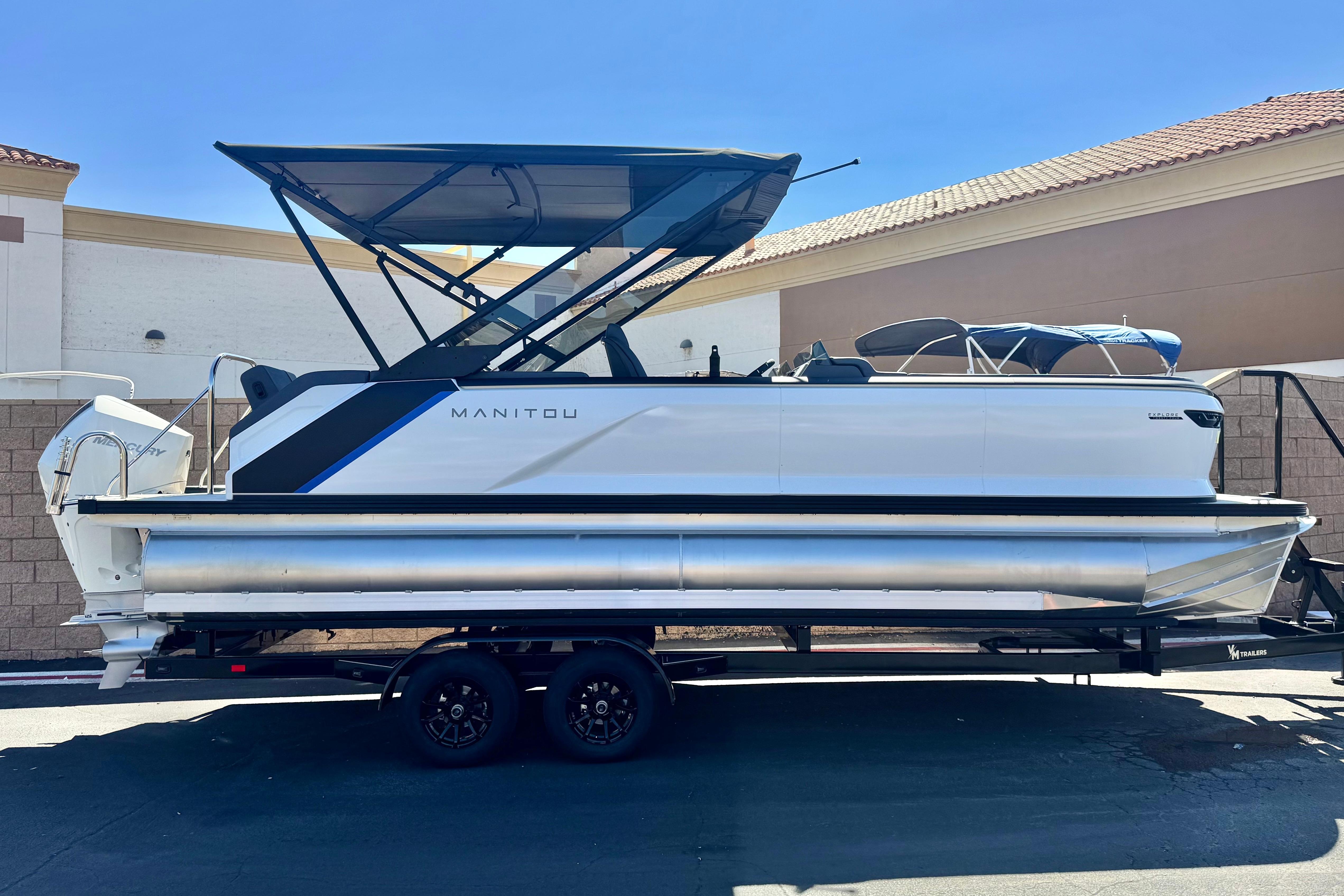 Manitou Explore 24 Navigator 2025 Manitou Explore 24 Navigator pontoon boat on trailer, side view, outdoor setting.