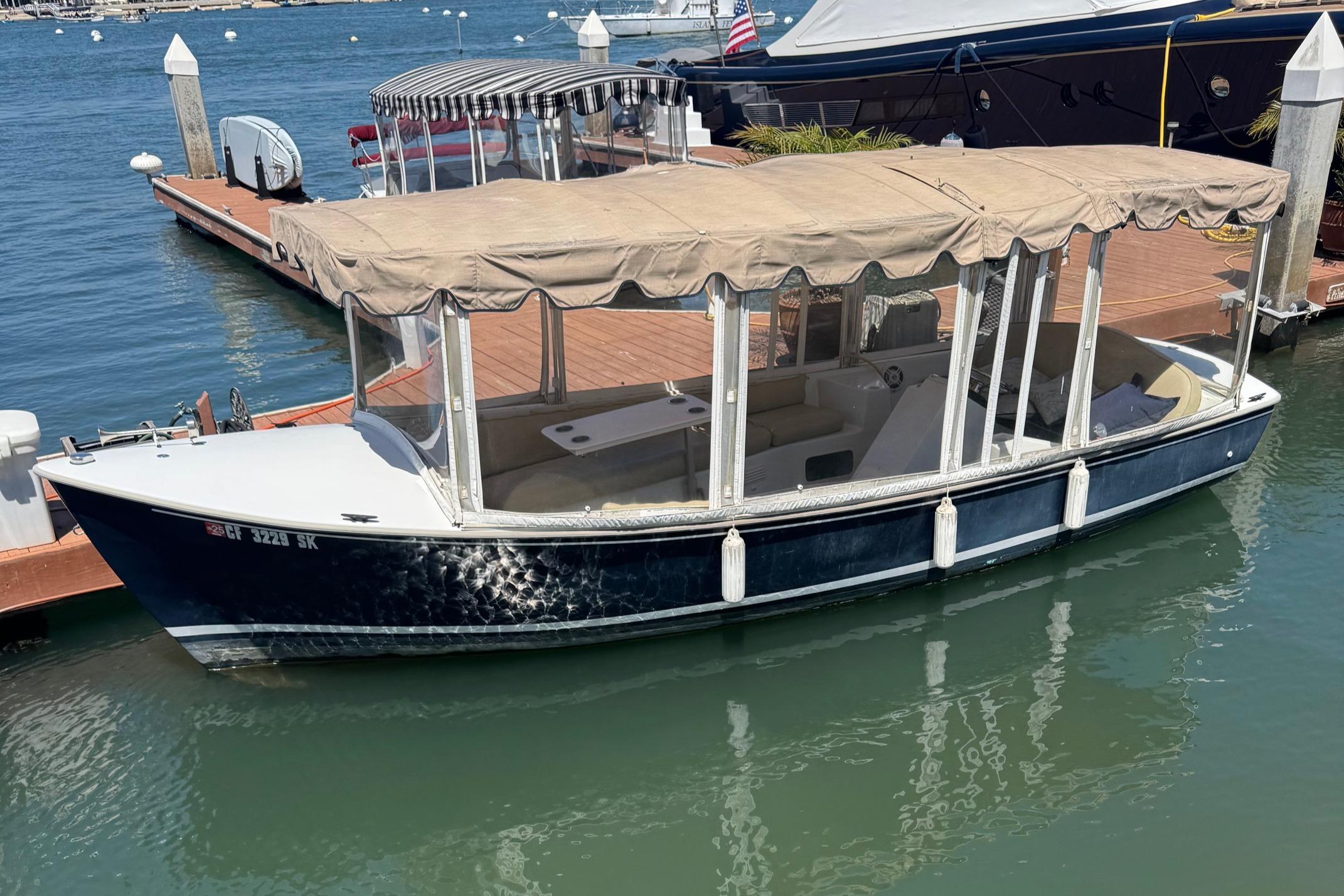 Duffy Classic 21 1994 Duffy Classic 21 electric boat docked in marina with beige canopy.