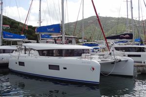 Lagoon 42 2020 Lagoon 42 catamaran docked in marina, surrounded by sailboats and lush hills.