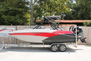 Starcraft SVX 230 OB 2025 Starcraft 230 boat on trailer, red and gray design, parked outdoors.