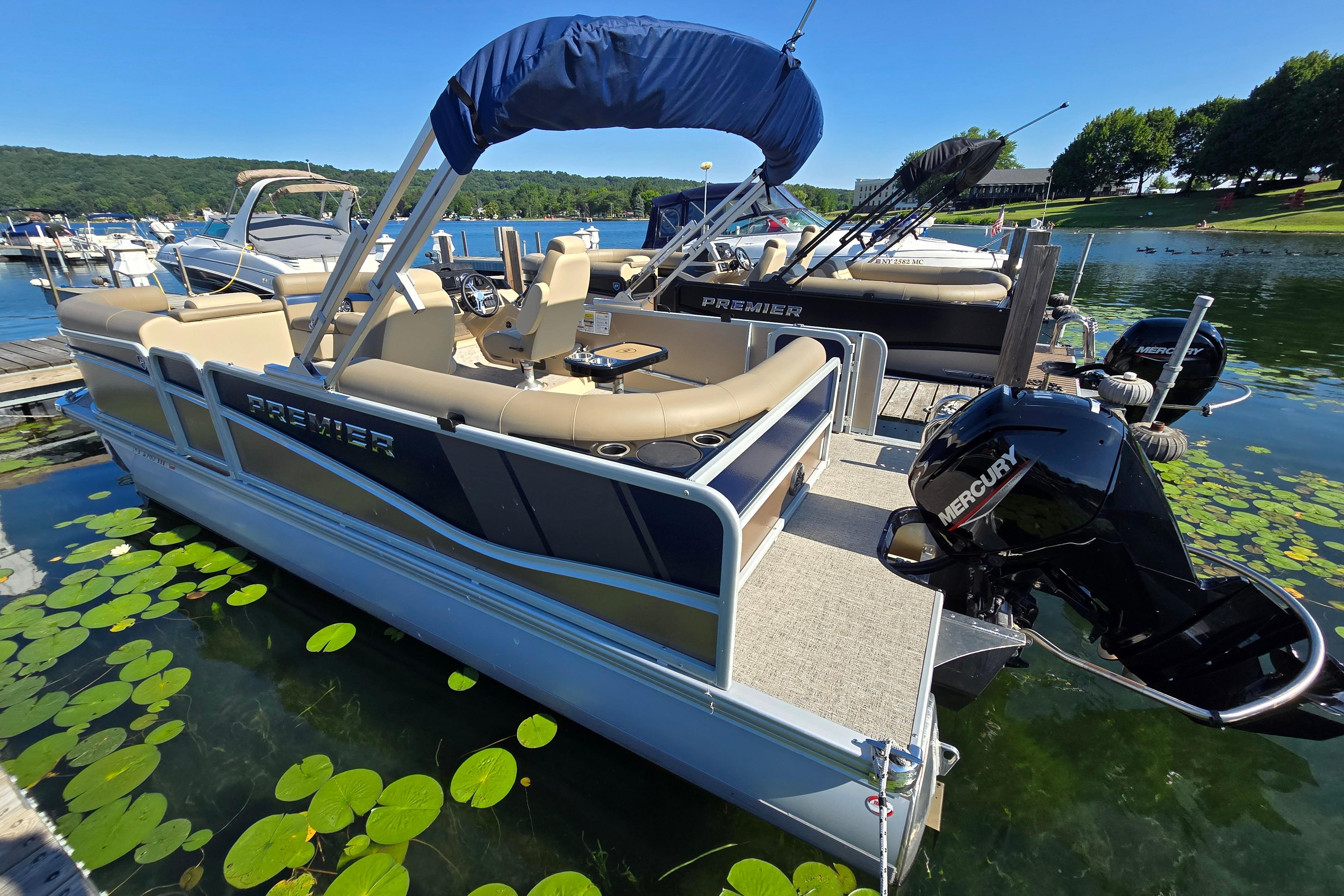 Premier 210 SunSation RE 2025 Premier 210 SunSation RE pontoon boat docked on a scenic lake.