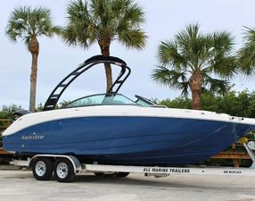 NauticStar 243 DC 2023 NauticStar 243 DC boat on trailer, surrounded by palm trees.