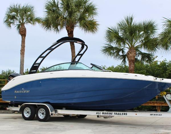 NauticStar 243 DC 2023 NauticStar 243 DC boat on trailer, surrounded by palm trees.