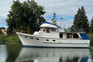 DeFever Pilot House 1979 De Fever Pilot House boat on calm water, surrounded by lush greenery.