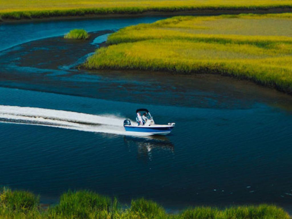 Key West 1720 Center Console 2026 Key West 1720 CC boat cruising through scenic marshland waterways.