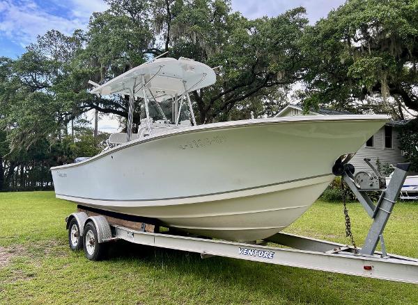 Regulator 23 2000 Regulator 23' Center Console boat on trailer, parked on grass with trees in background.