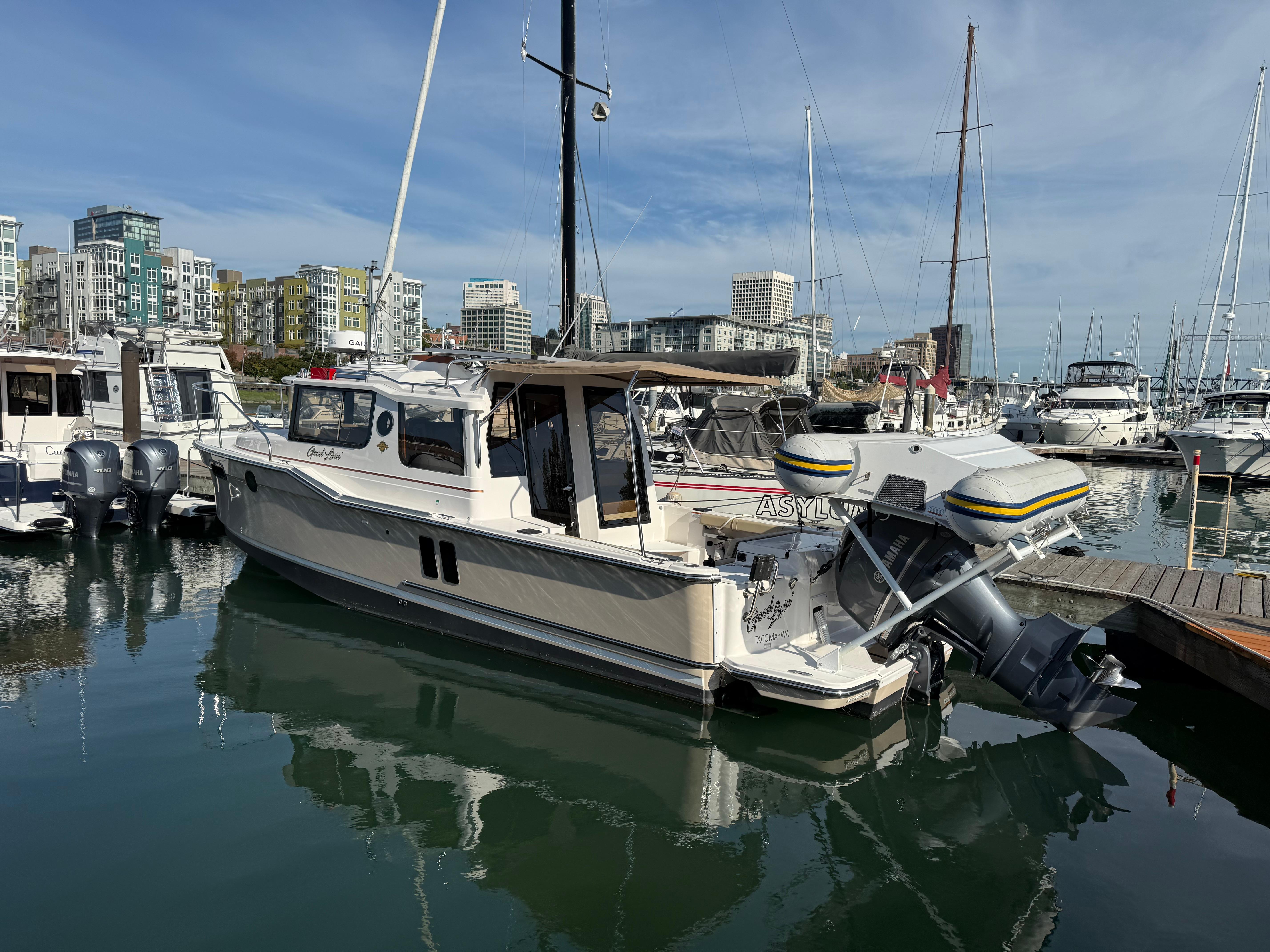 Ranger Tugs R-27 2021 Ranger Tugs R-27 boat docked in a marina with cityscape background.