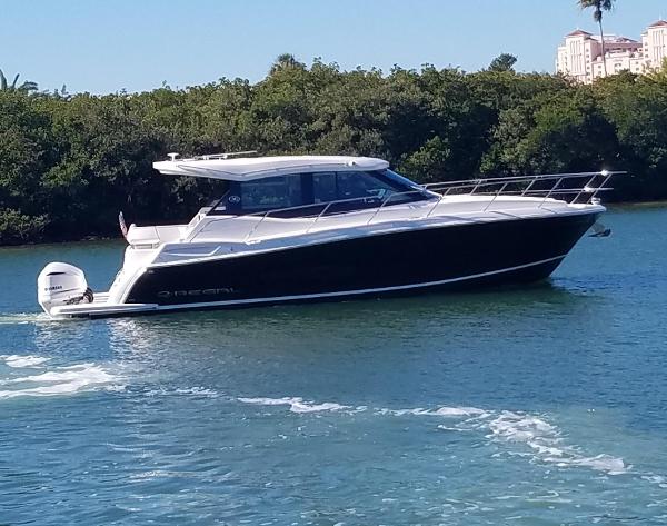 Regal 38 XO 2021 Regal 38 XO boat cruising on a sunny day, surrounded by lush greenery.