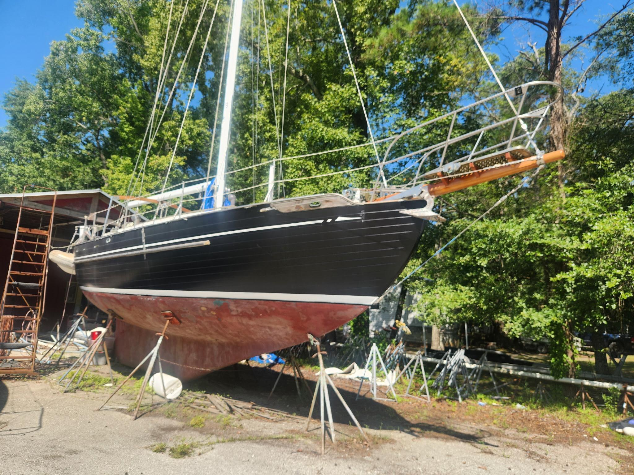 Tayana 37 1976 Tayana 37 sailboat on stands, surrounded by trees and a clear blue sky.