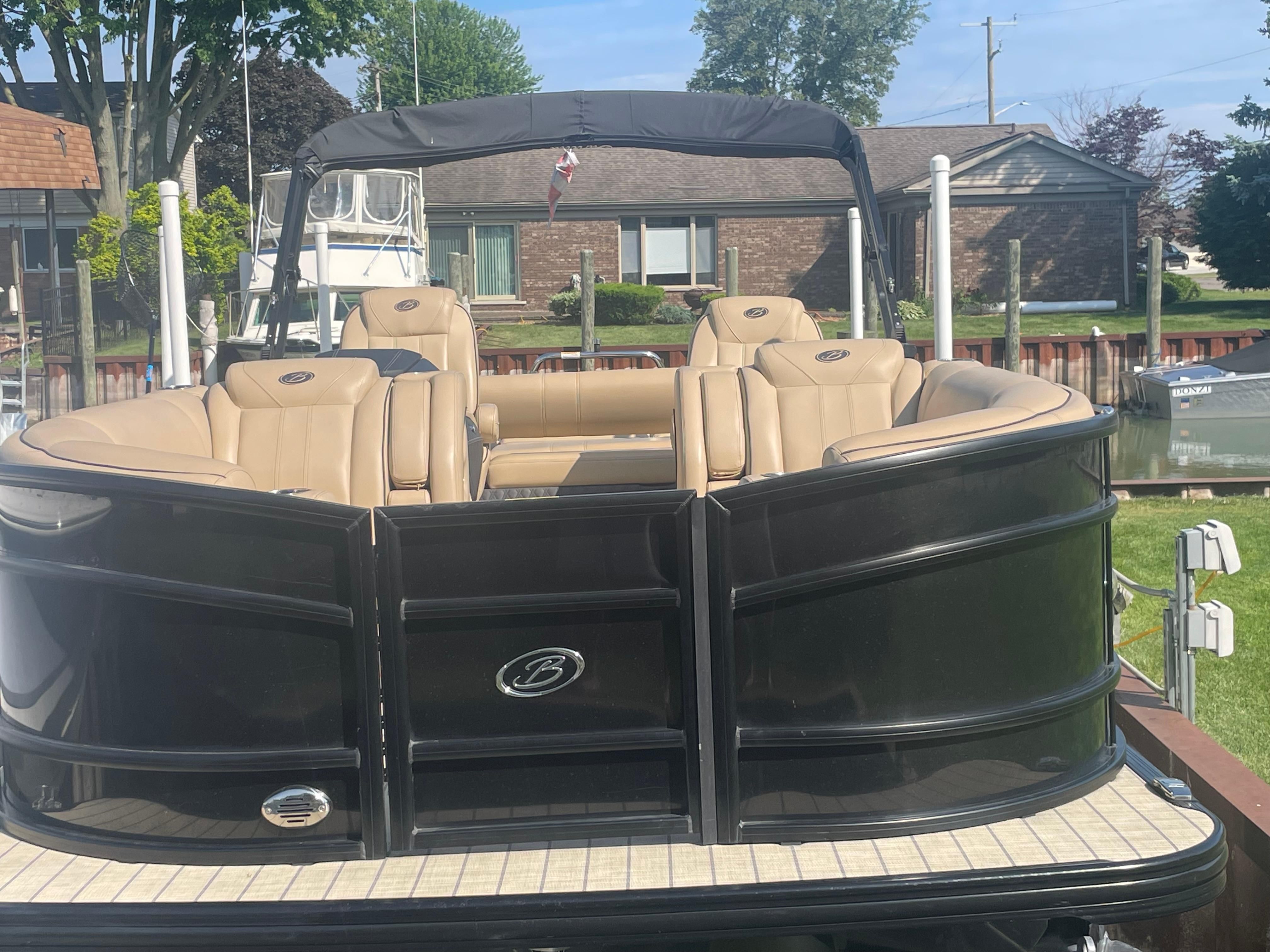 Barletta Lusso U23UC 2019 Barletta Lusso U23UC pontoon boat with tan seating, docked near a residential area.
