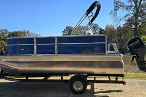 Sun Tracker Party Barge 16 DLX 2026 Sun Tracker Party Barge 16 DLX pontoon boat on trailer, blue and silver design.