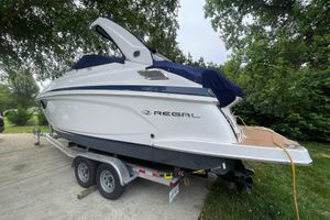 Regal 28 Express 2019 Regal 28 Express boat on trailer, parked outdoors with trees in the background.