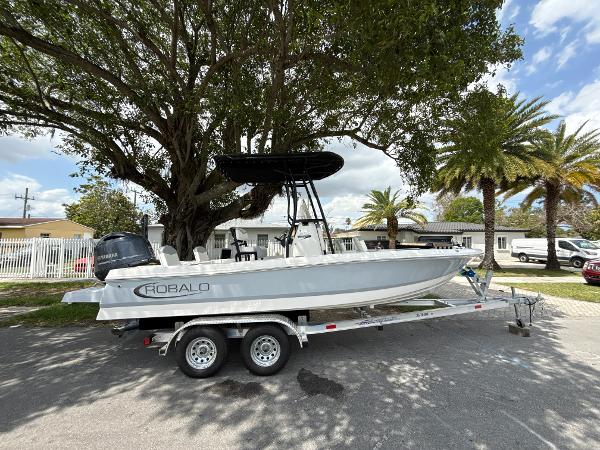 Robalo 206 Cayman 2022 Robalo 206 Cayman boat on trailer under trees, parked in residential area.