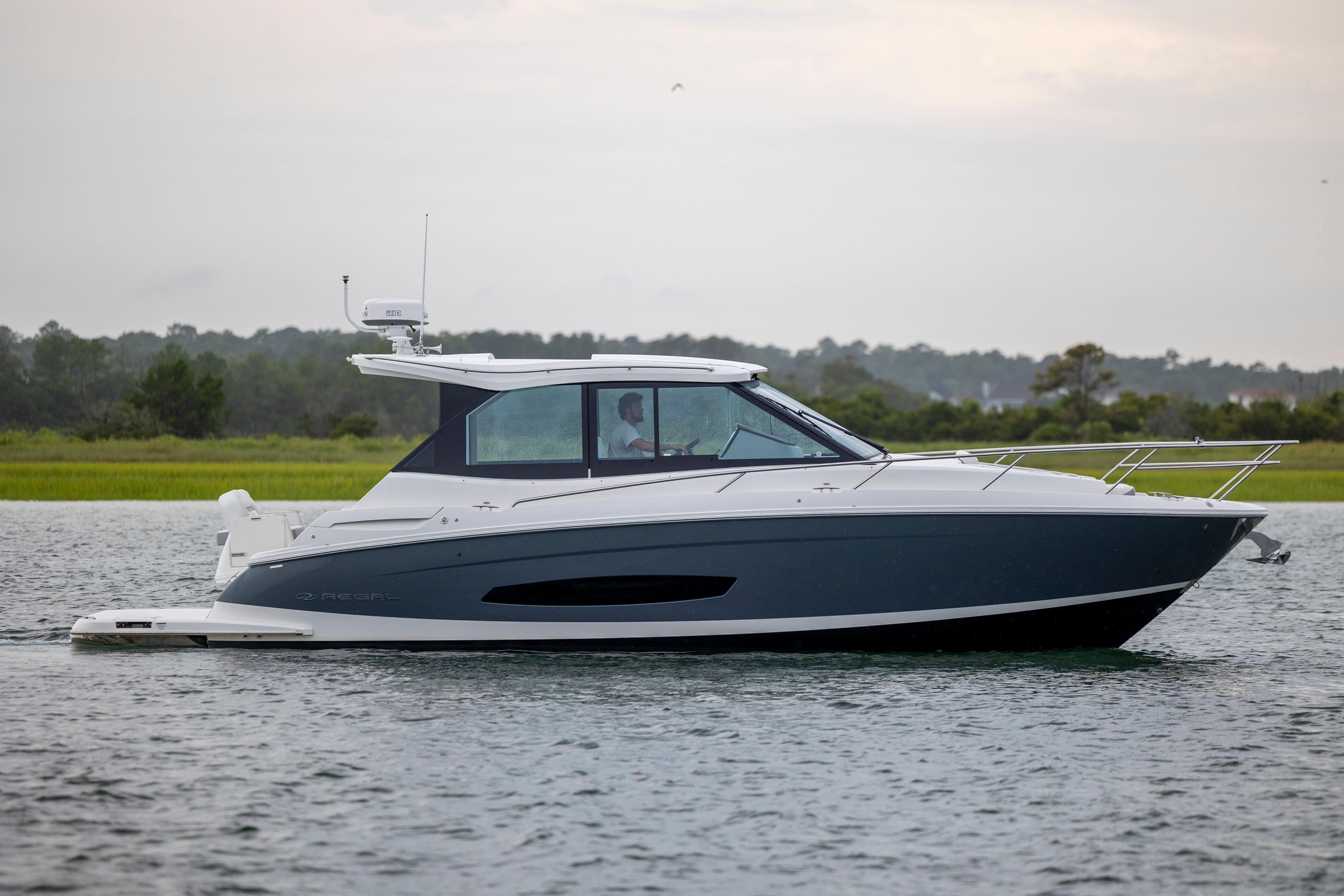 Regal 36 Grande Coupe 2022 Regal 36 Grande Coupe cruising on a calm lake with lush greenery in the background.