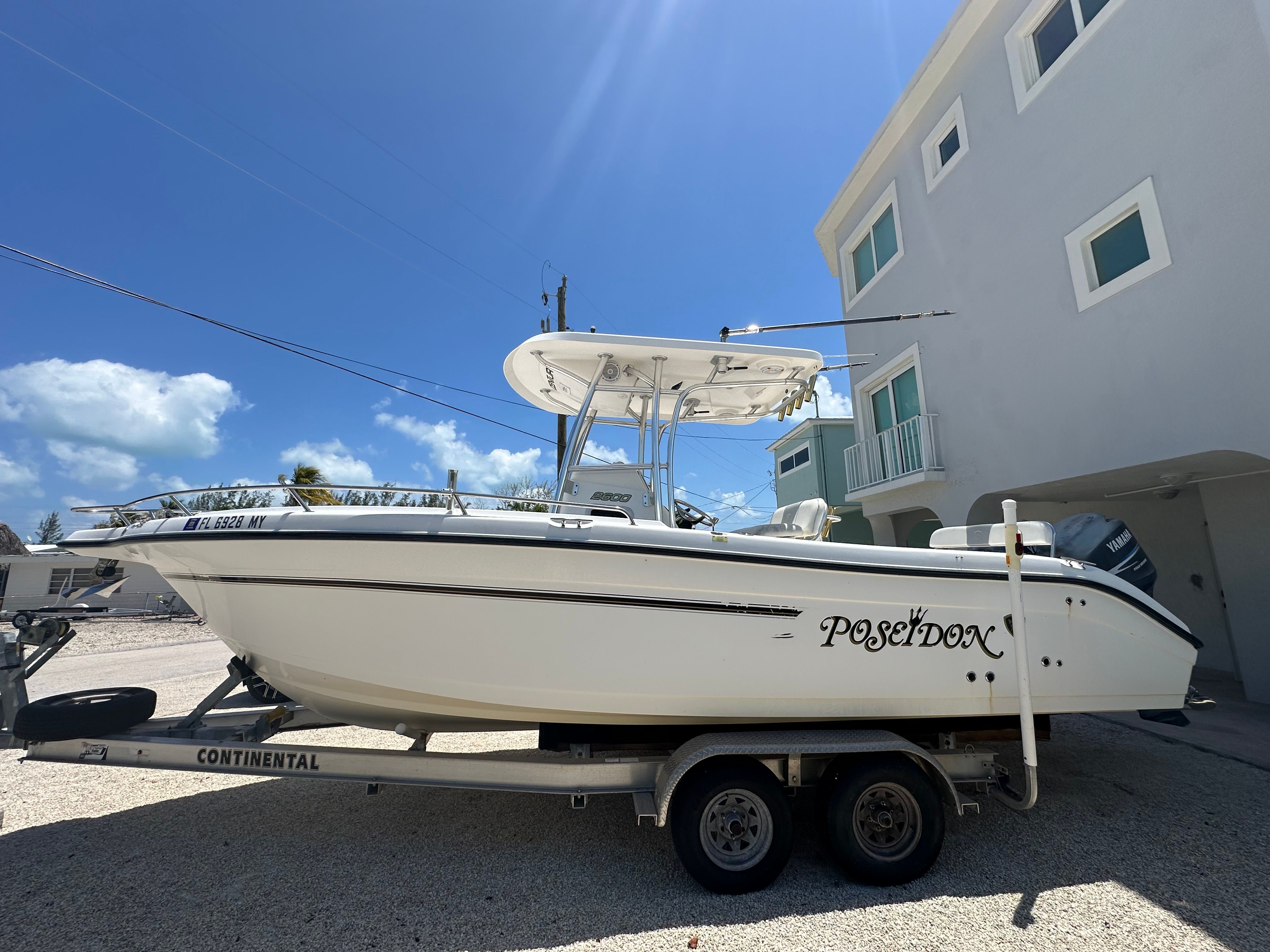 Century 2600 CC 2005 Century 2600 CC boat named Poseidon on trailer, parked near a building under blue sky.