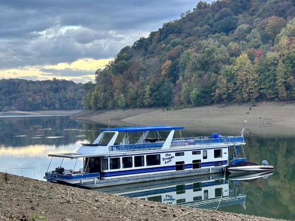 Stardust Cruisers 16x77 Houseboat 1998 Stardust Cruisers 16x77 houseboat on a serene lake with forested hills.