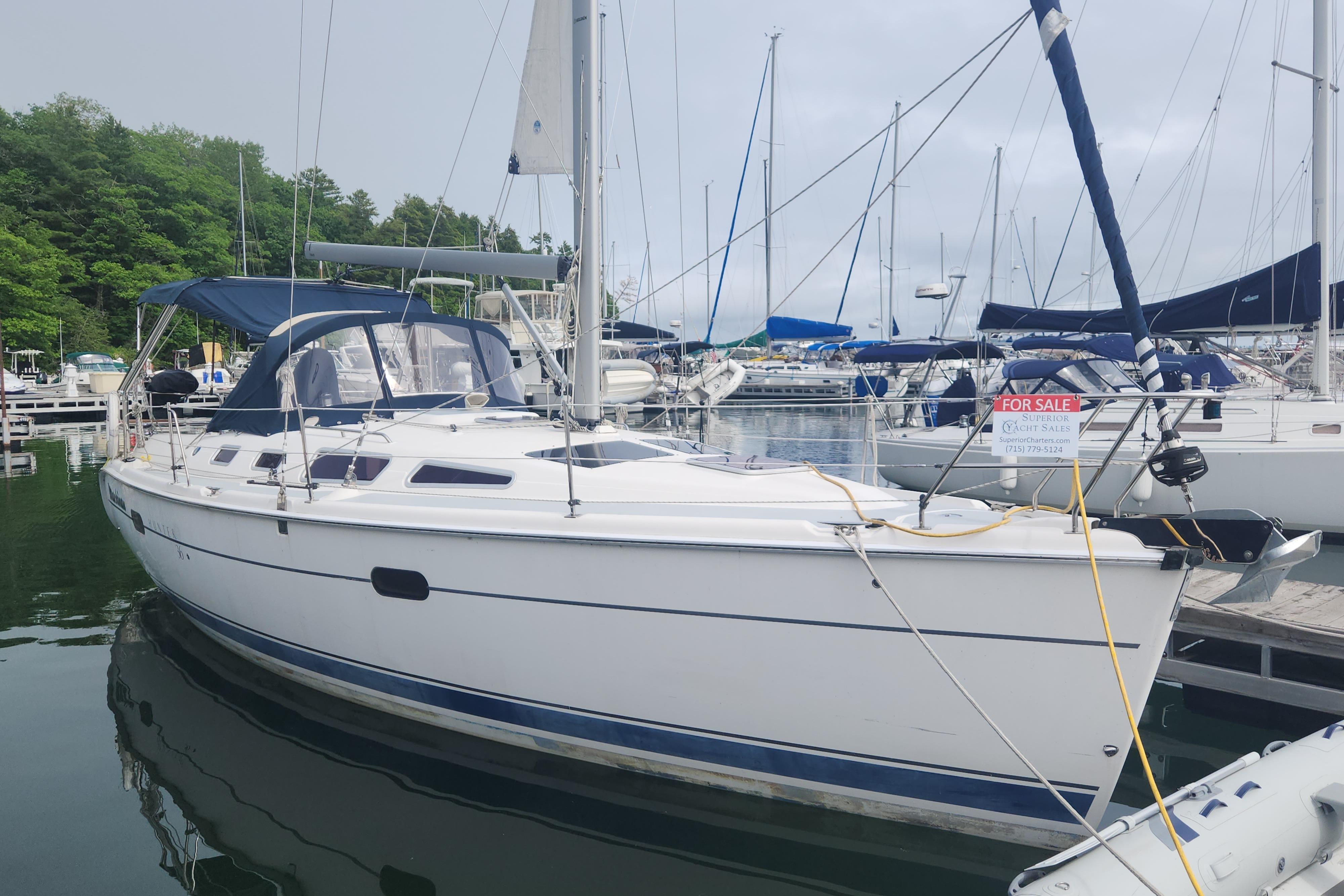 Hunter 36 2004 Hunter 36 sailboat docked, for sale, with blue canopy and lush green background.