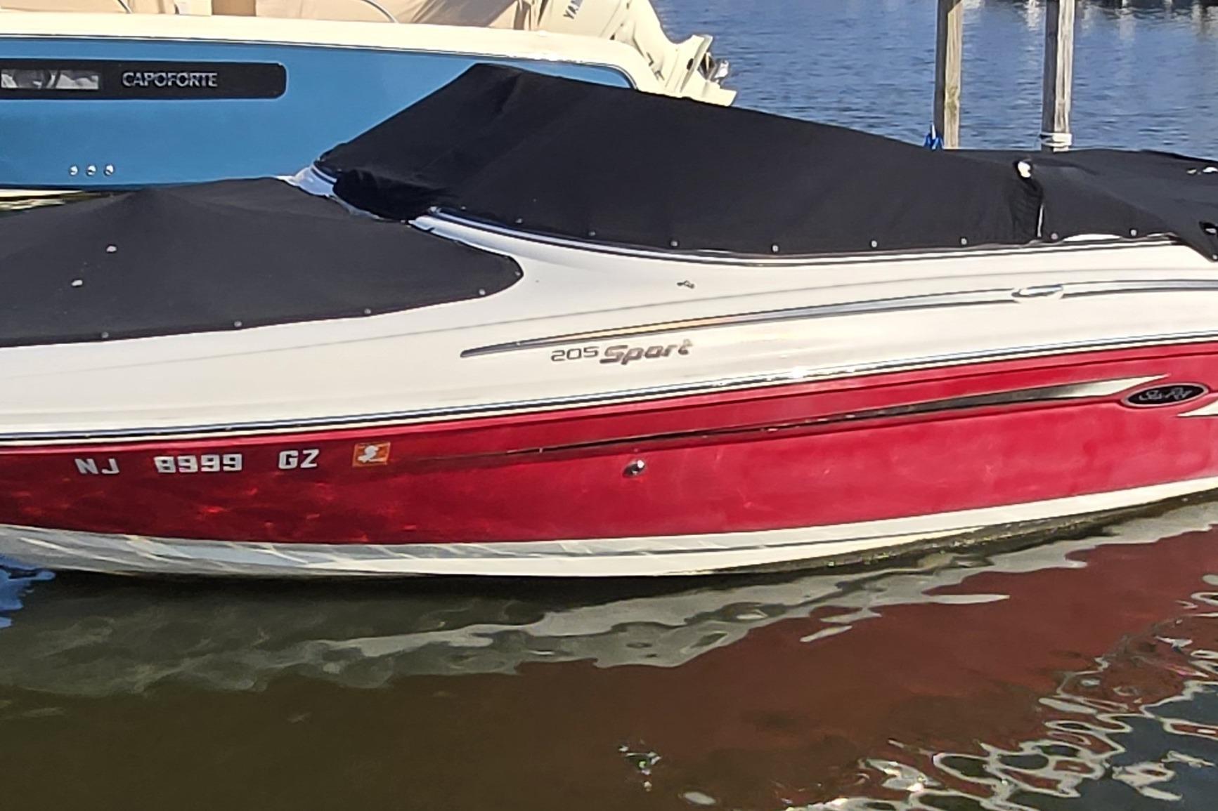Sea Ray 205 Sport 2007 Sea Ray 205 Sport boat with red hull and black cover docked in water.