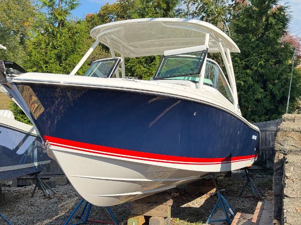 Pursuit DC 246 Dual Console 2025 Pursuit DC 246 Dual Console boat with blue hull and red stripe, displayed outdoors.