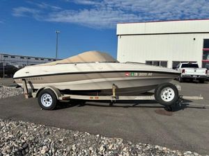Reinell 180 2000 Reinell 180 boat on trailer, parked outdoors near a building.