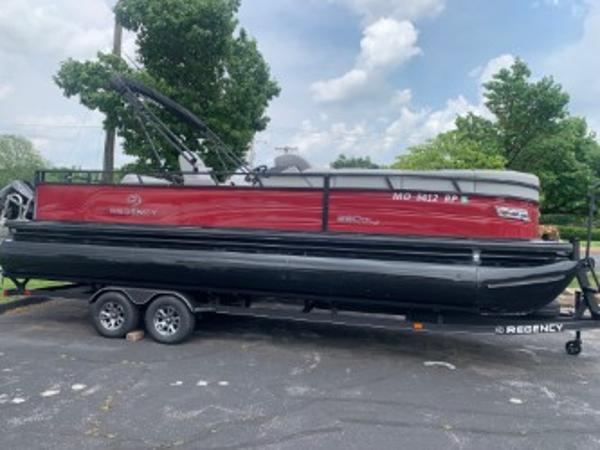 Regency 250DL3 2024 Regency 250DL3 pontoon boat on trailer, parked outdoors under a cloudy sky.