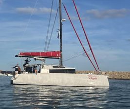 NEEL 43 2023 NEEL 43 trimaran with red sails on calm water, clear sky background.