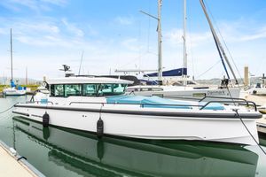 Axopar 37 2023 Axopar 37 boat docked in marina, surrounded by sailboats under a clear sky.