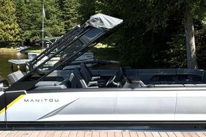 Manitou Explore 24 Navigator 2023 Manitou Explore 24 Navigator pontoon boat docked by a scenic lakeside.
