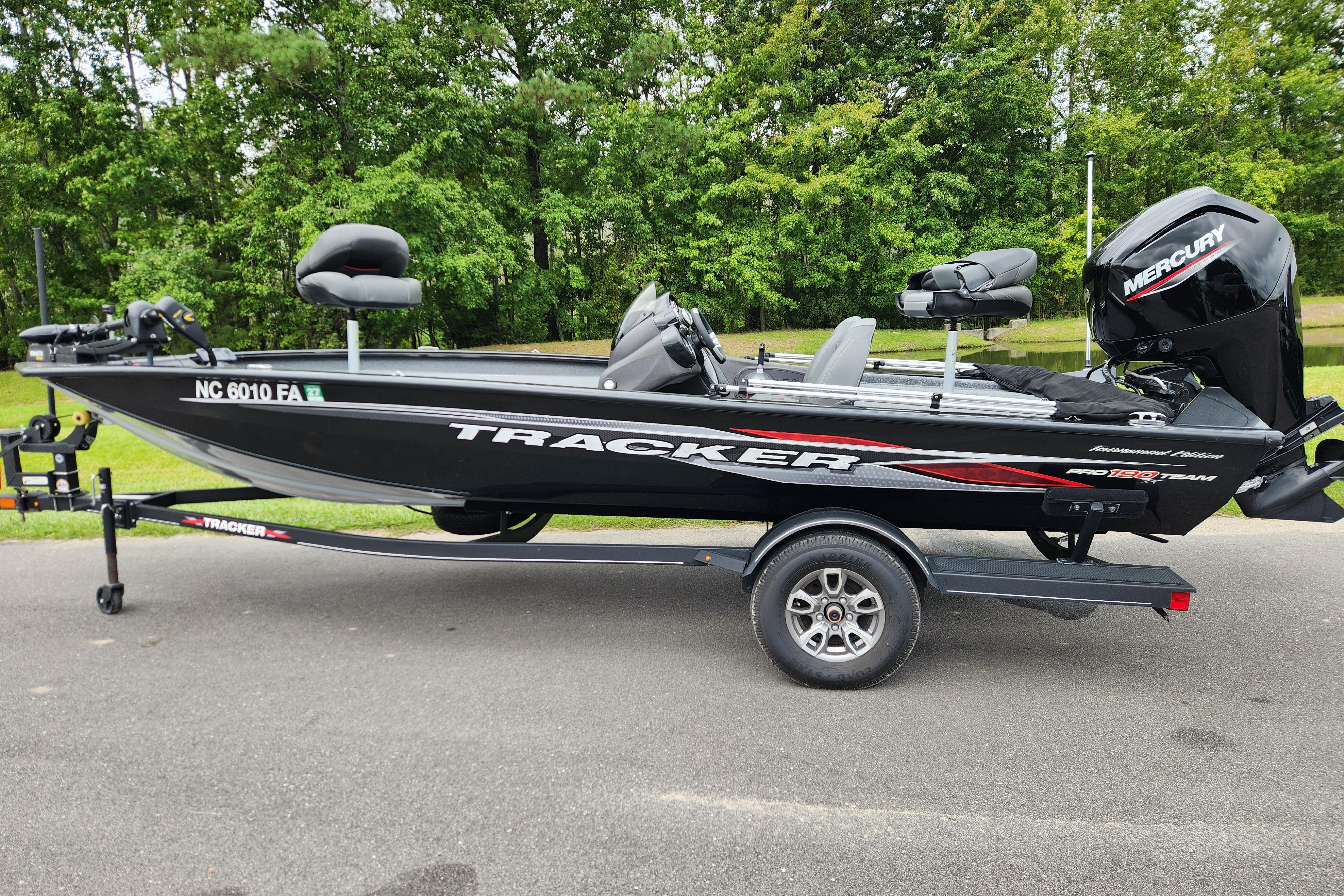 Tracker Pro Team 190 TX 2023 Tracker Pro Team 190 TX boat on trailer, parked on road with green trees background.