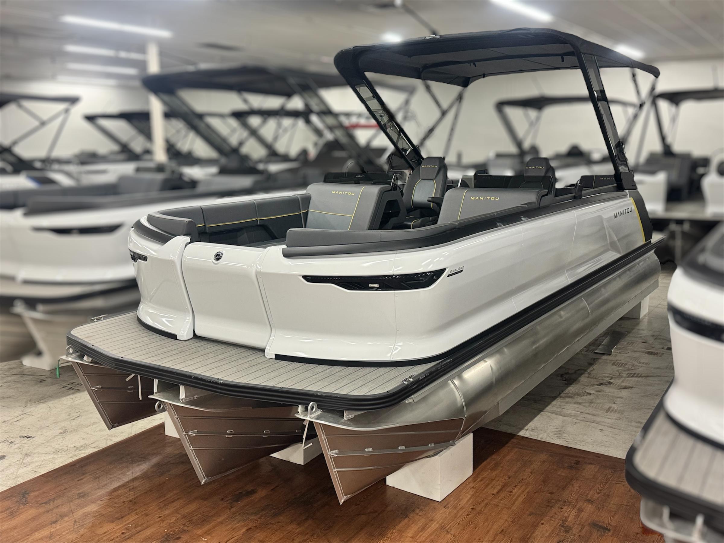 Manitou Explore 24 Navigator 2025 Manitou Explore 24 Navigator pontoon boat in showroom, featuring sleek design and modern seating.