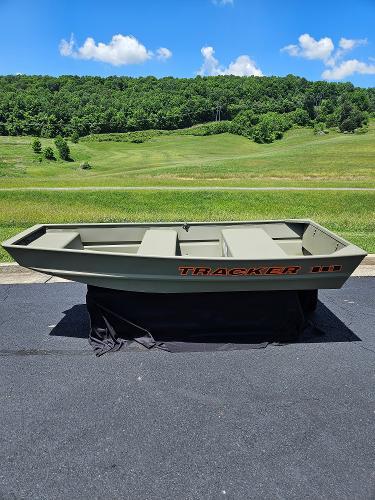 Tracker Grizzly 1036 Utility 2025 Tracker Grizzly 1036 Utility boat on pavement, green landscape background.
