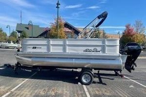Sun Tracker Party Barge 18 DLX 2026 Sun Tracker Party Barge 18 DLX pontoon boat on trailer in parking lot.