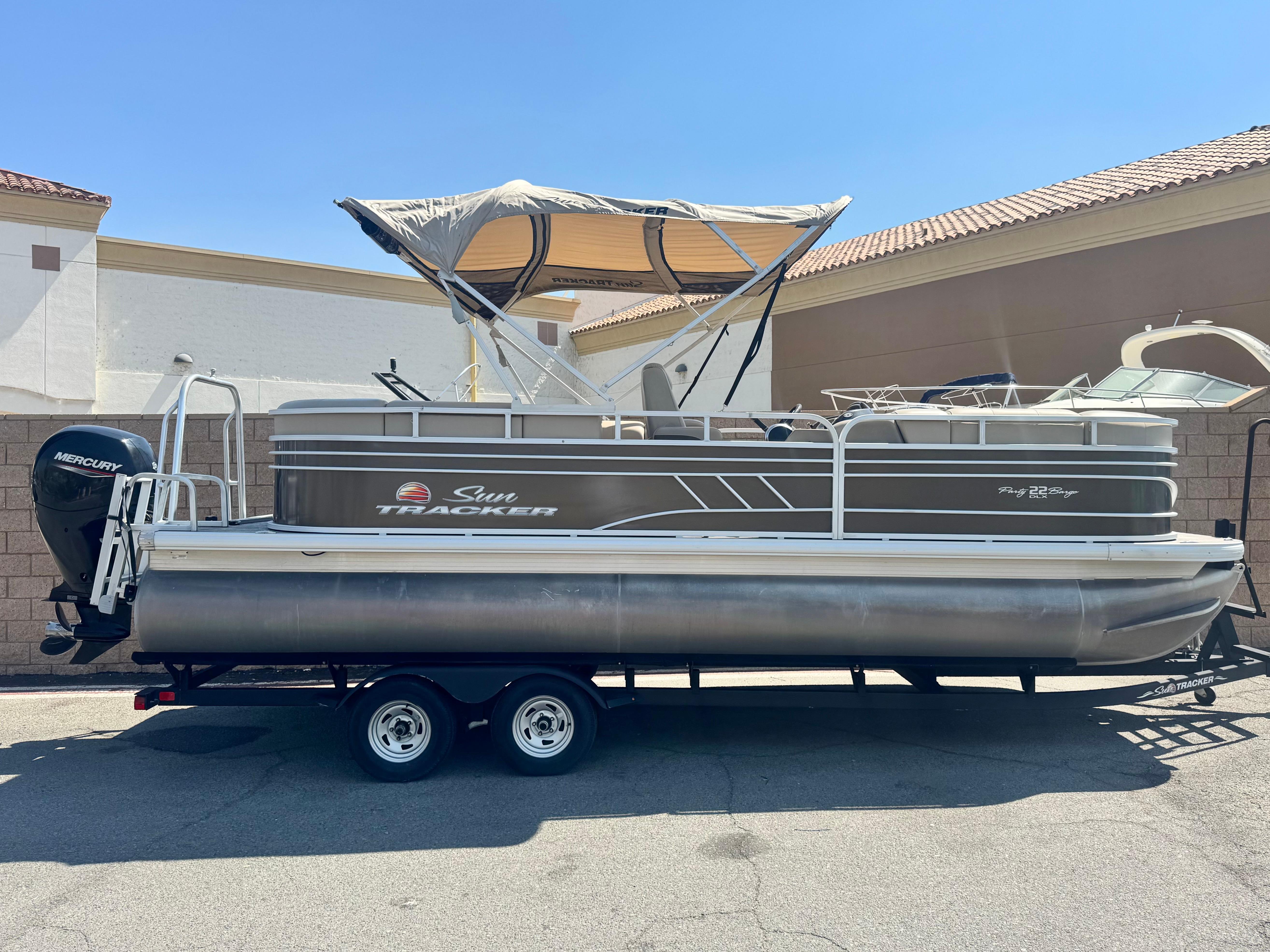 Sun Tracker Party Barge 22 DLX 2021 Sun Tracker Party Barge 22 DLX pontoon boat on trailer, parked outdoors.