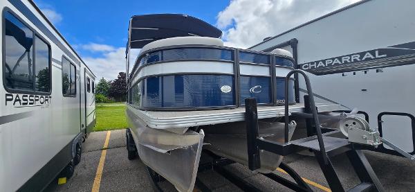 Crest Classic LX 220 SLC 2021 Crest Classic LX 220 SLC pontoon boat parked between RVs under a blue sky.