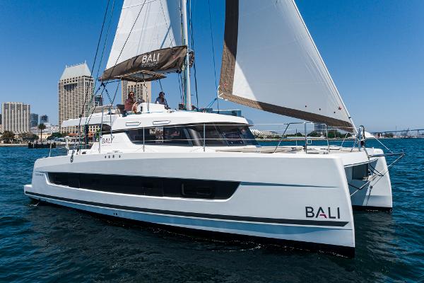 Bali CATSPACE 2025 Bali CATSPACE catamaran sailing in a city harbor, clear blue sky.