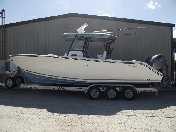Cobia 301 Center Console 2021 Cobia 301 Center Console boat on trailer, parked outside a metal building.