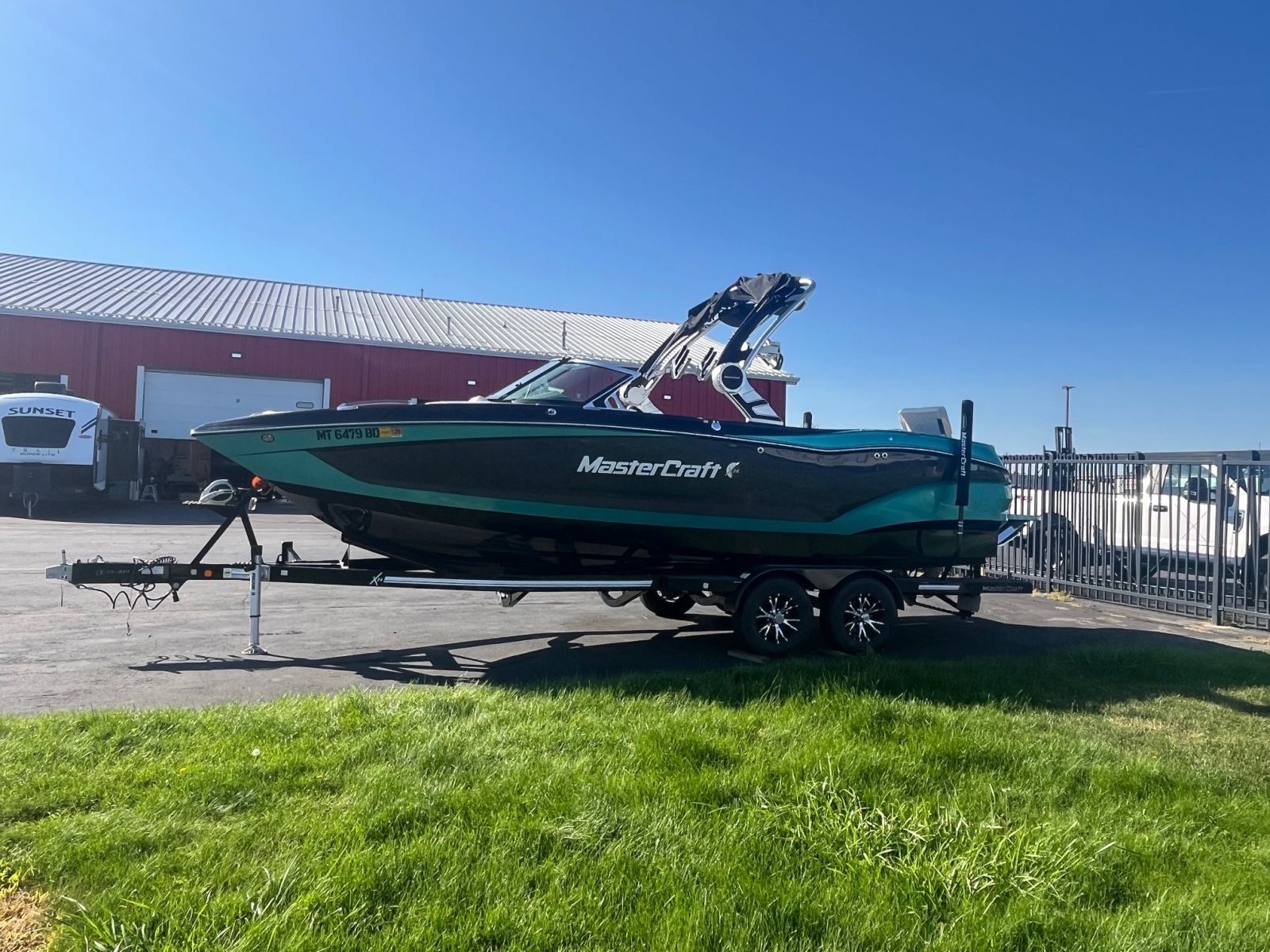 MasterCraft Mastercraft X24 2019 MasterCraft X24 boat on trailer, parked outdoors near a red building.