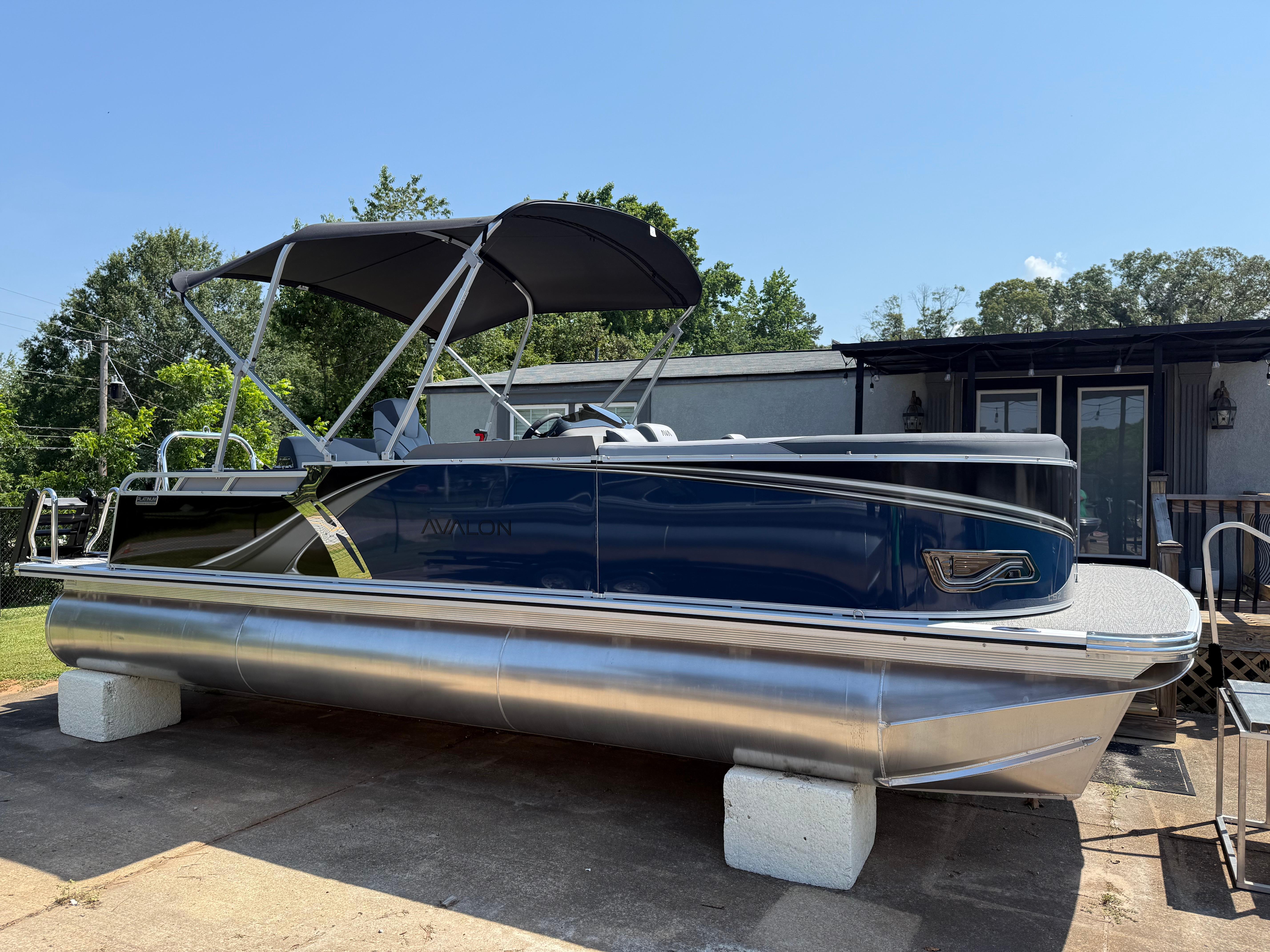 Avalon LSZ Cruise Bench 2025 Avalon LSZ Cruise Bench pontoon boat with canopy, parked on concrete blocks.