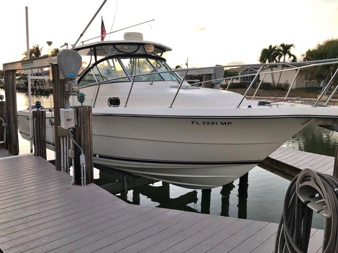 Pursuit 3070 Offshore 2004 Pursuit 3070 Offshore boat docked at marina, surrounded by calm water and palm trees.