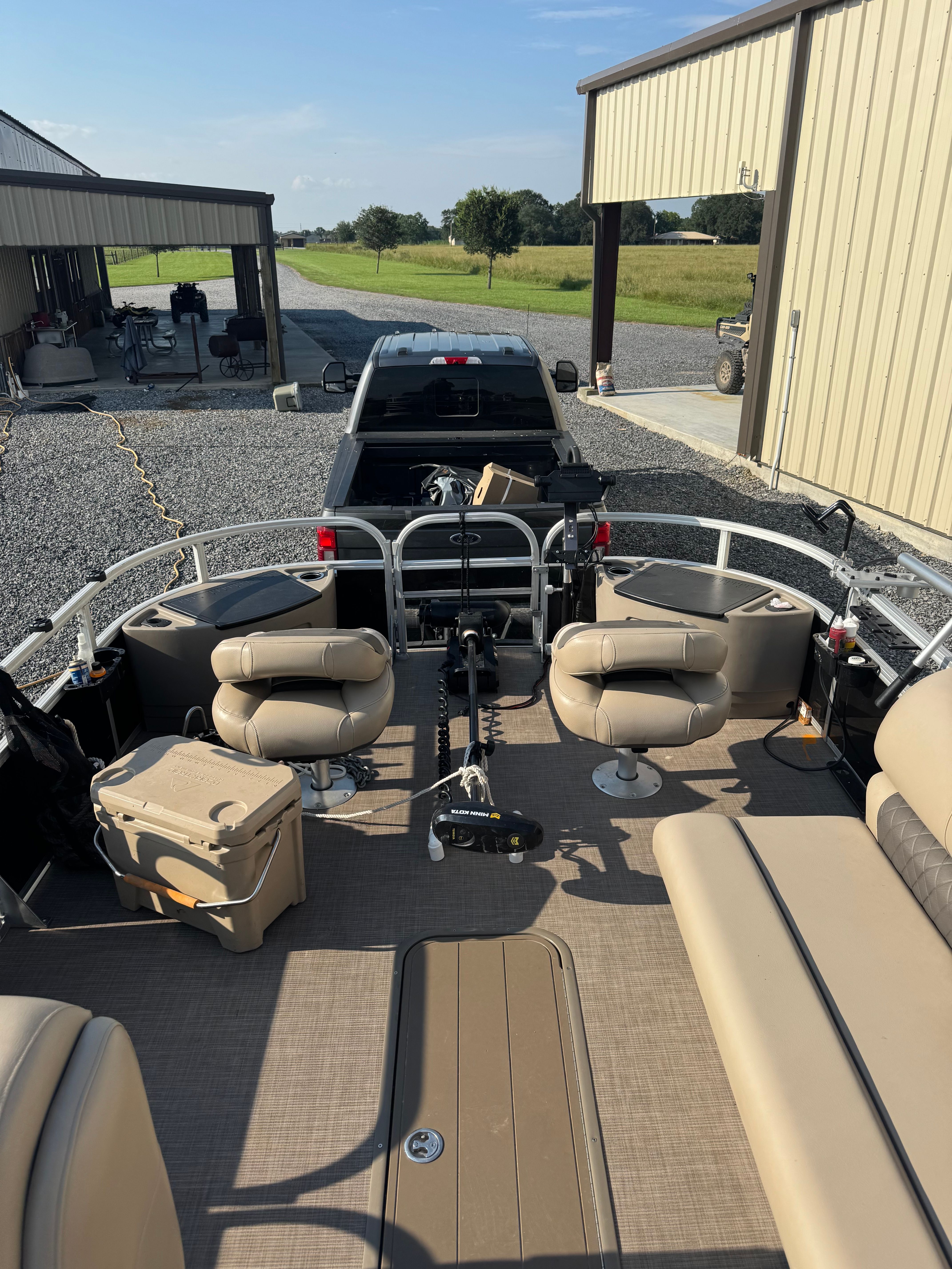 Sun Tracker Party Barge 24 XP3 2021 Sun Tracker Party Barge 24 XP3 pontoon boat with beige seating, parked near a truck.