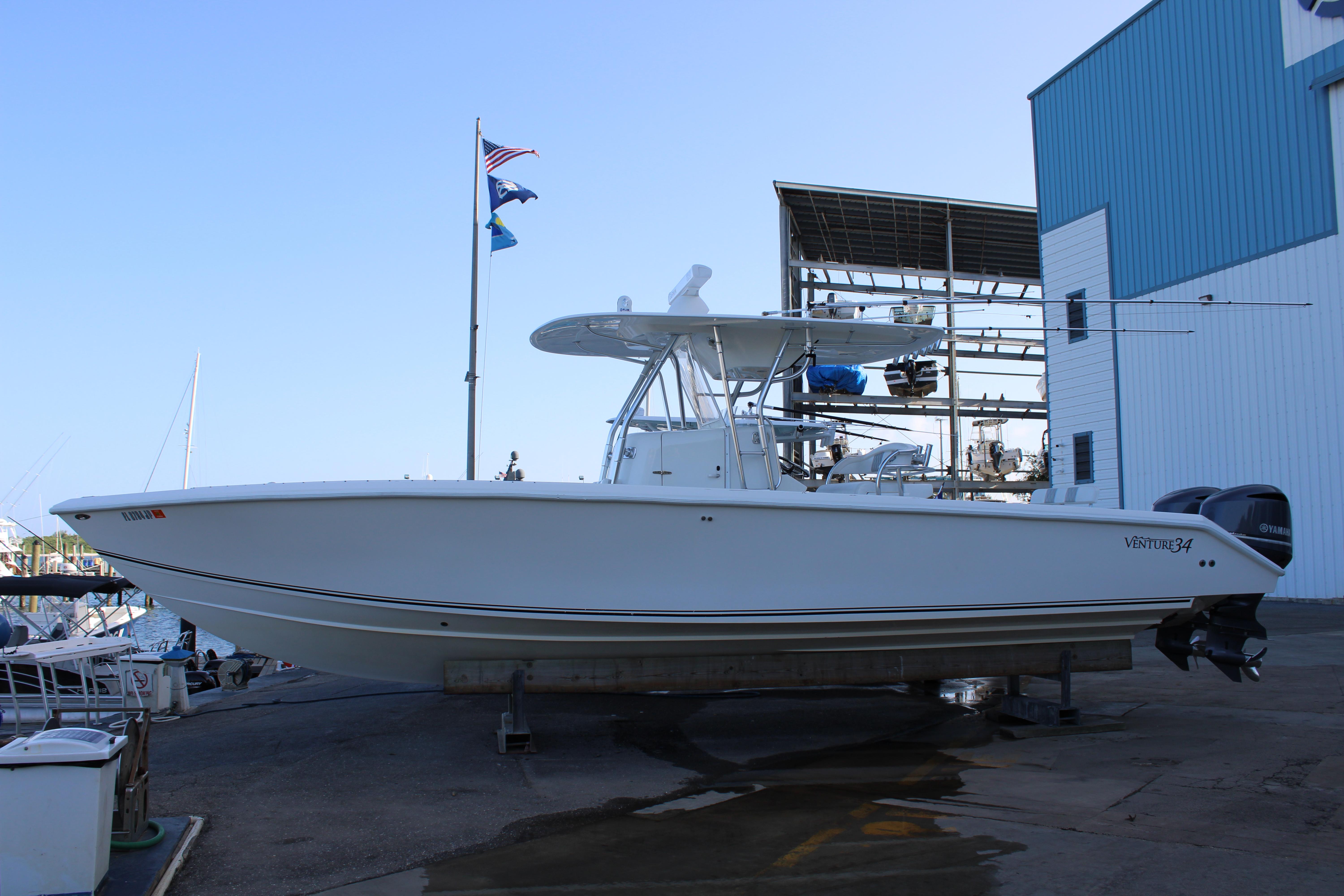 Venture 34 Open 1998 Venture 34 Open boat docked at marina with flags and blue sky.