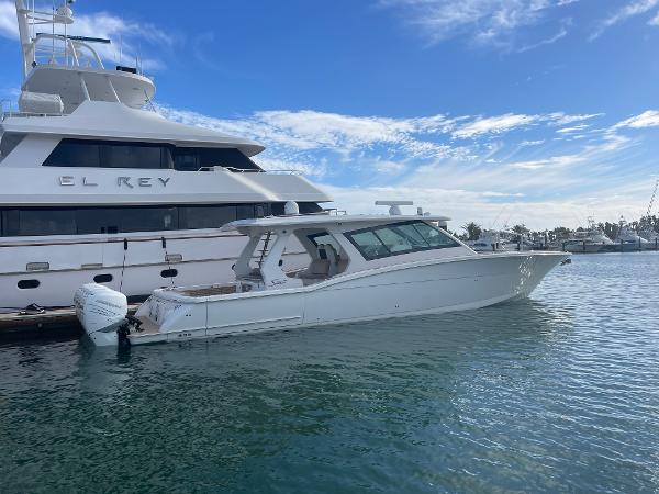 Scout 530 LXF 2020 Scout 530 LXF boat docked beside a large yacht on a sunny day.