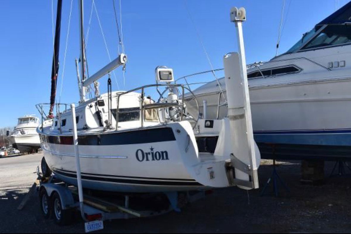 Hake / Seaward 26RK 2016 Hake Seaward 26RK sailboat "Orion" on trailer, docked beside another boat.